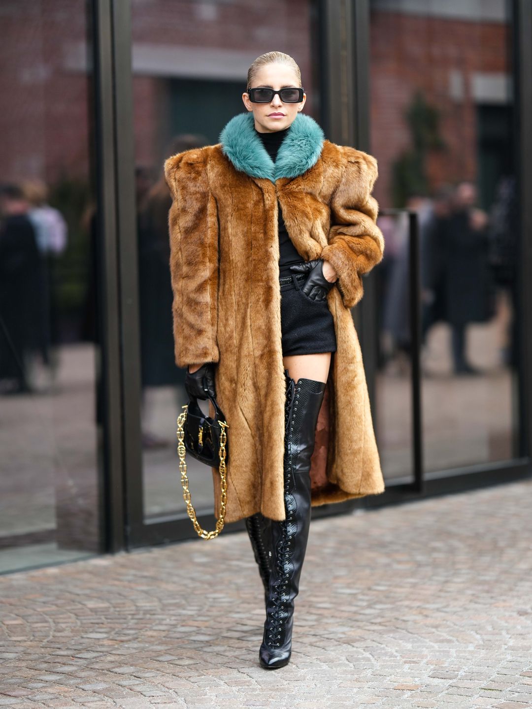 Woman wearing brown fluffy coat with blue collar and thigh-high boots 