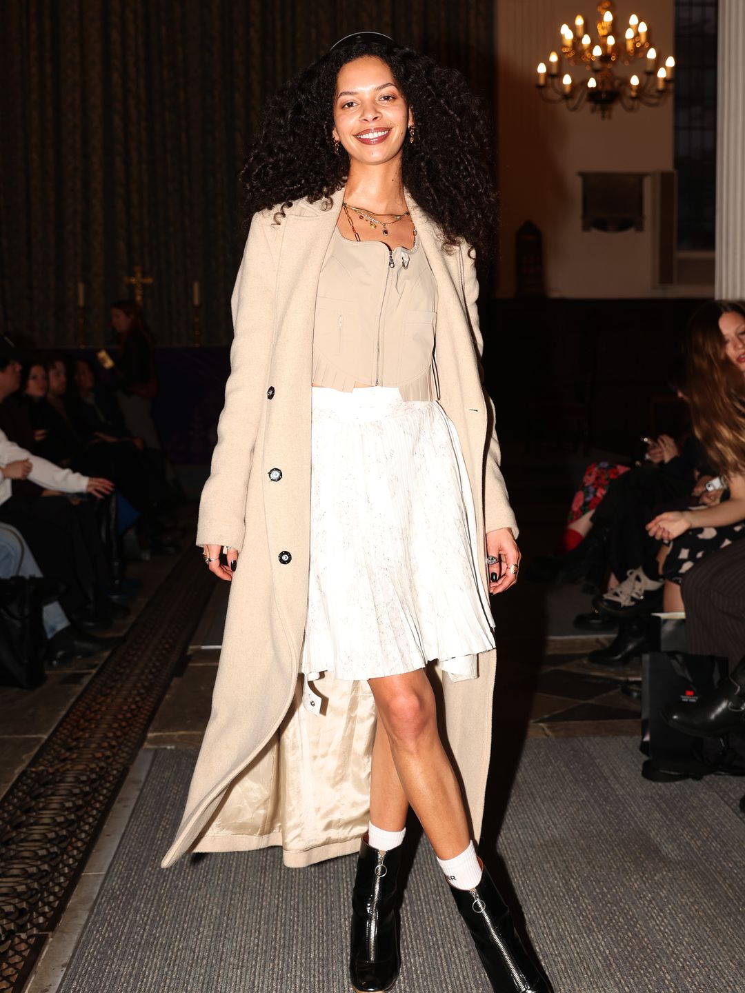 Alexandra Beaton attends the 3M x Momonary AW24 show  in black boots, a camel coat and camel coloured corset top