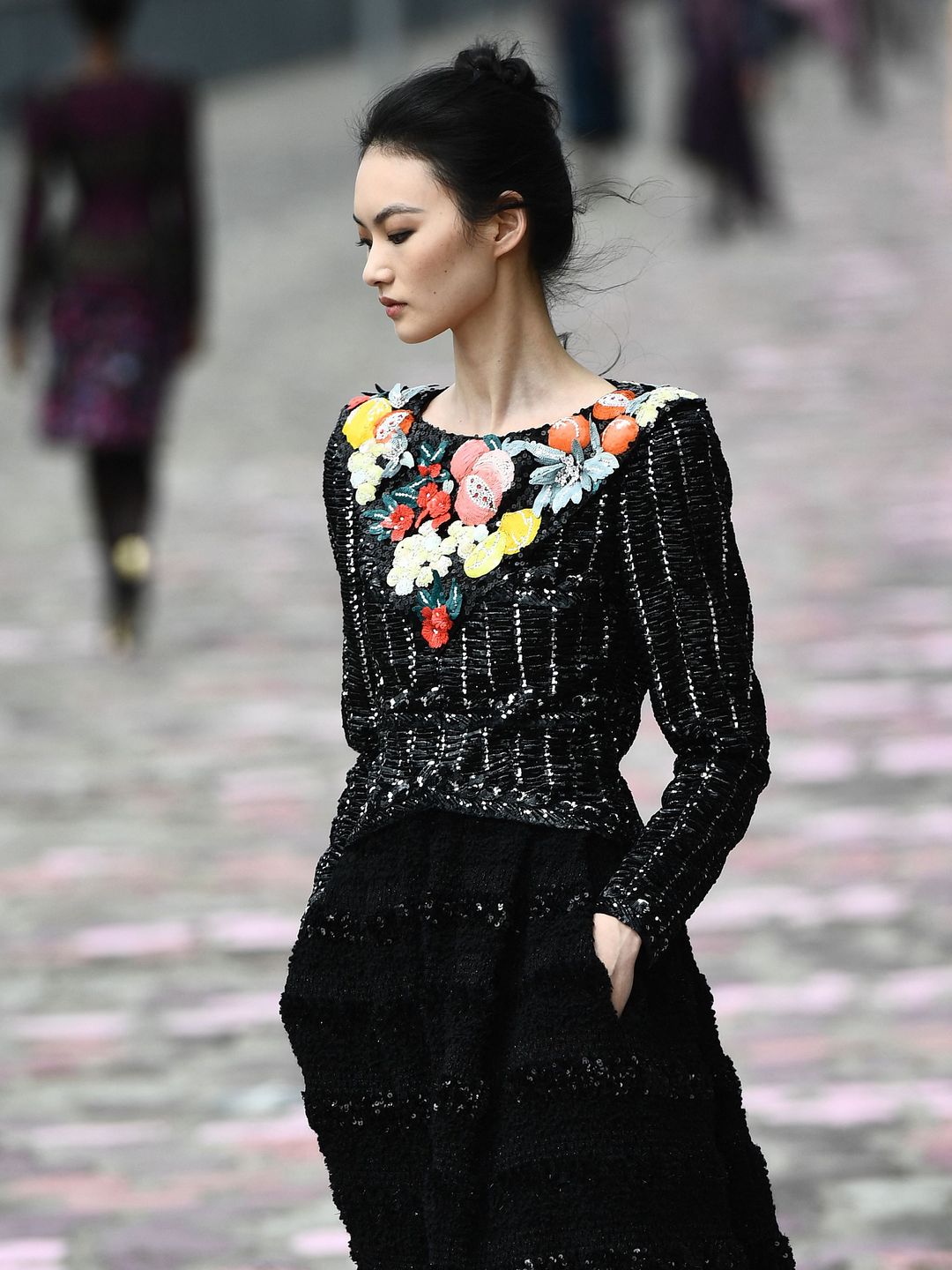 Chanel model wearing black blouse with vibrant embellishment 