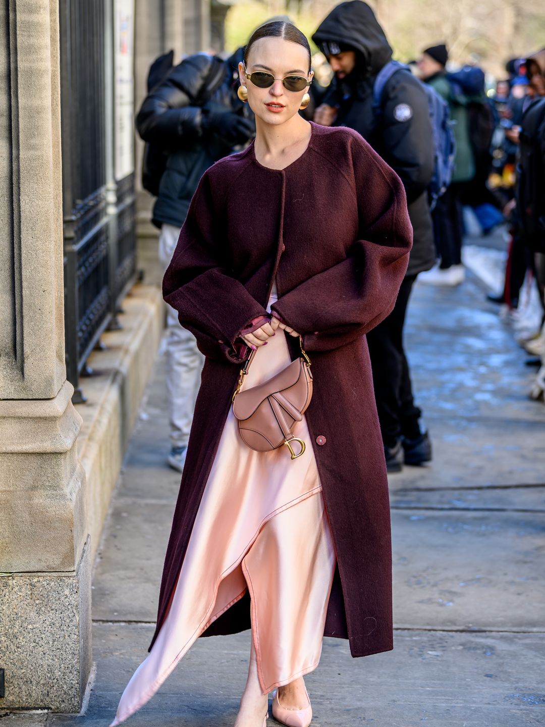 Abi Hoffman wears a purple coat and a pink ensemble as she poses outside the Bevza Fashion show