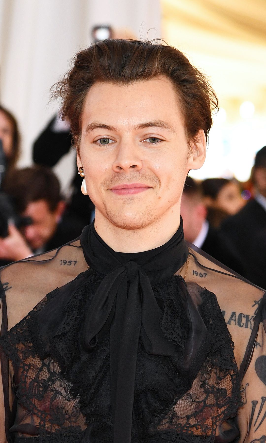 Harry Styles at the 2019 Met Gala wearing a sheer Gucci blouse and a single pearl earring.