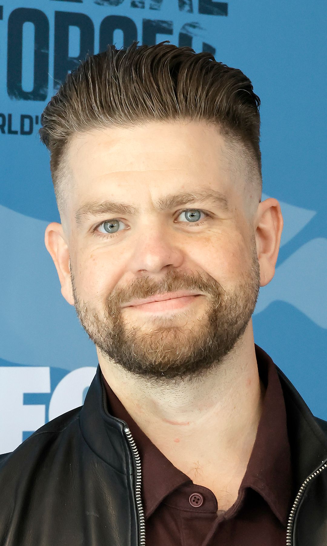 Jack Osbourne in a leather jacket and crimson shirt