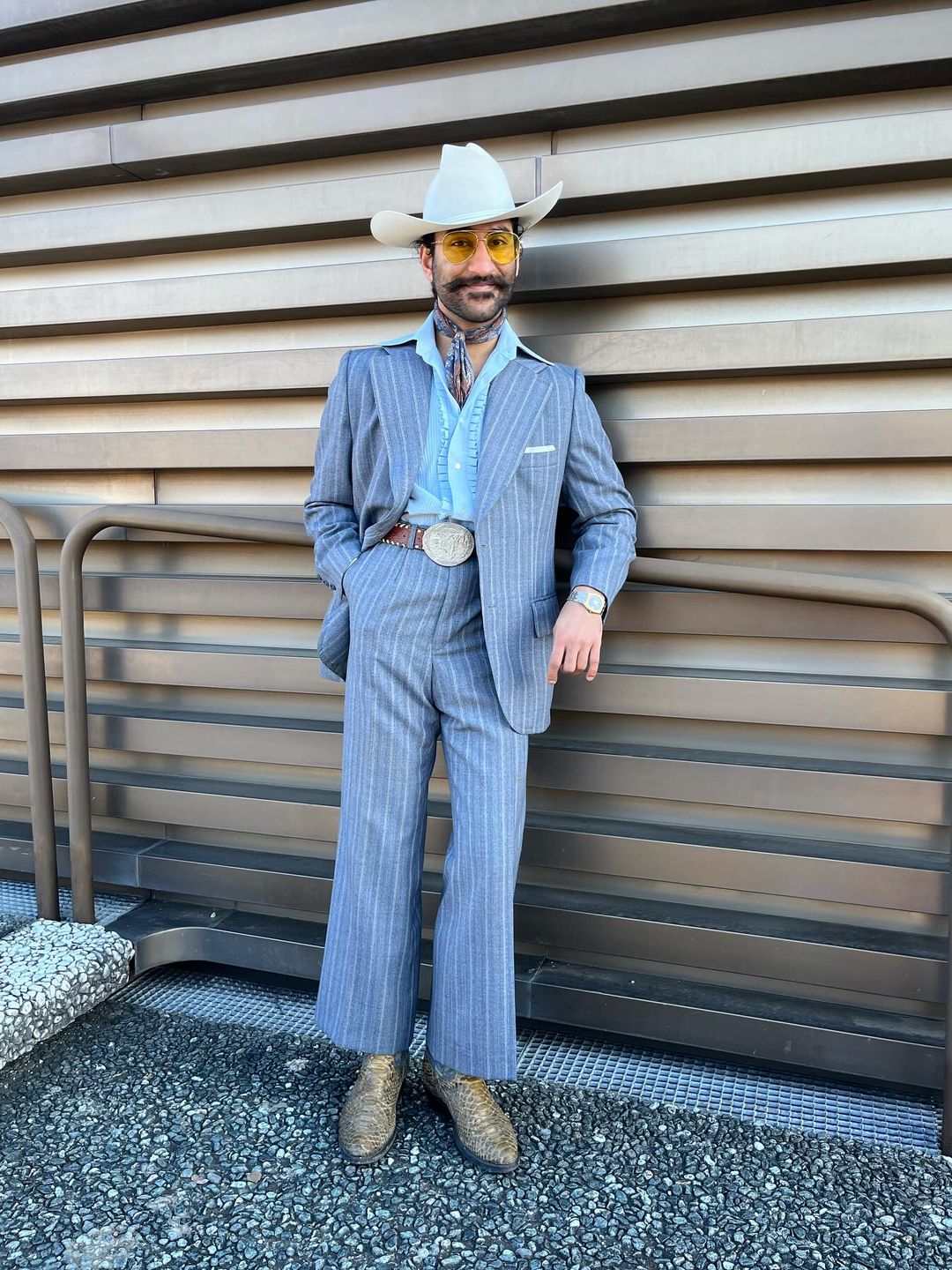 A guest wears a blue suit, cowboy hat, silk neck tie and snakeskin cowboy boots to Pitti Uomo in Florence