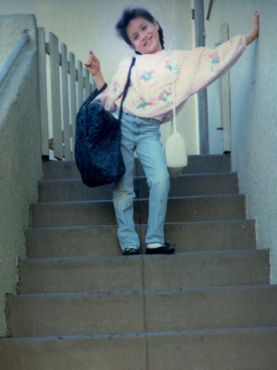 A young Meghan Markle posing with bags on a set of stairs