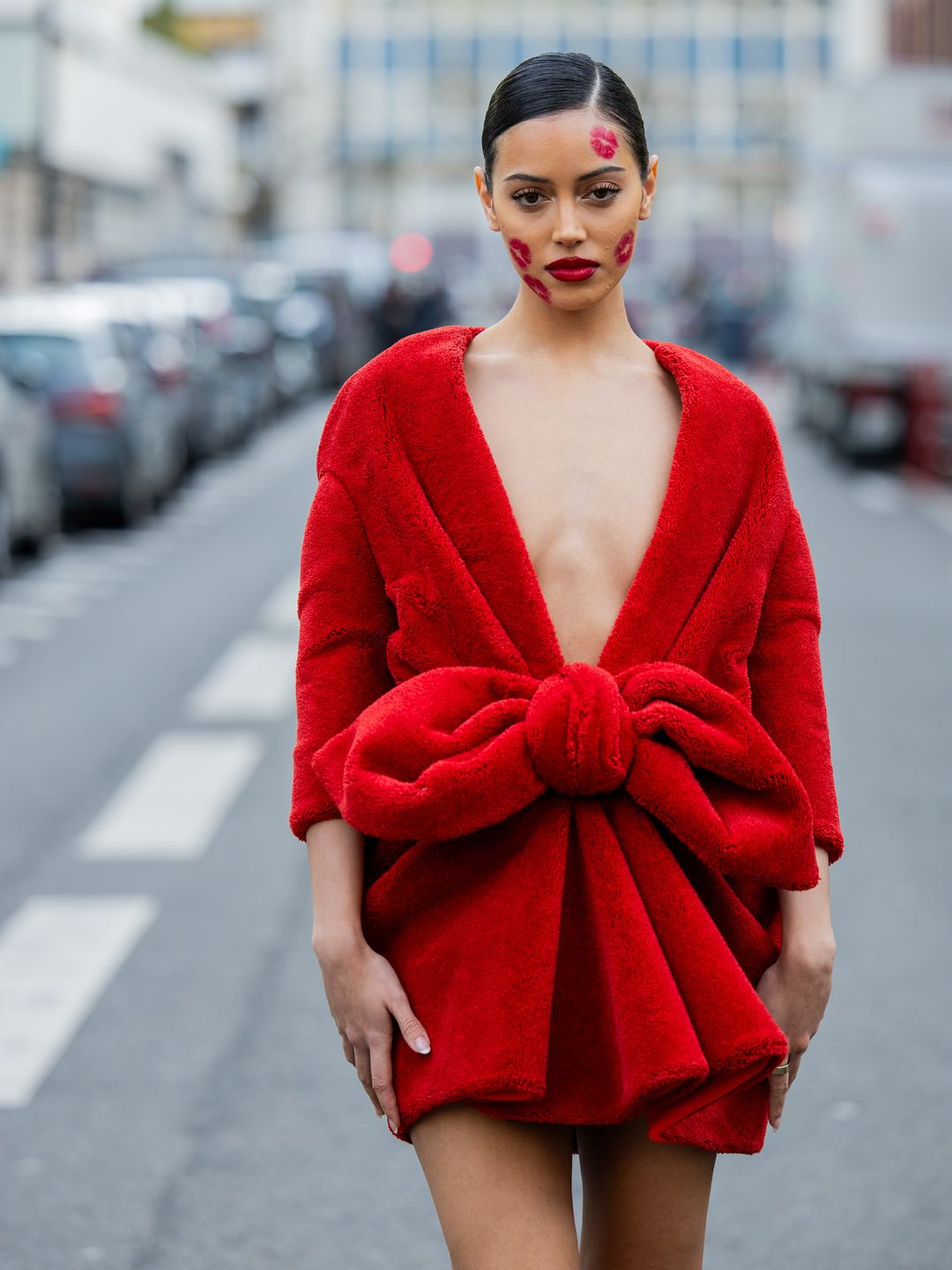 Christian Vierig wears a bright red mini dress adorned with a ginat bow to the Viktor & Rolf show in Paris