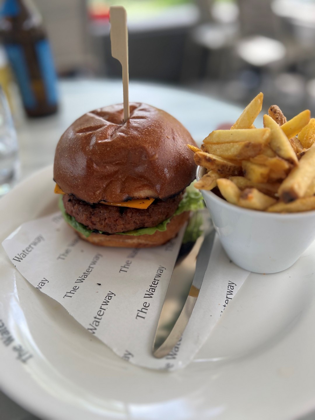 A hamburger placed next to a small bowl of chips
