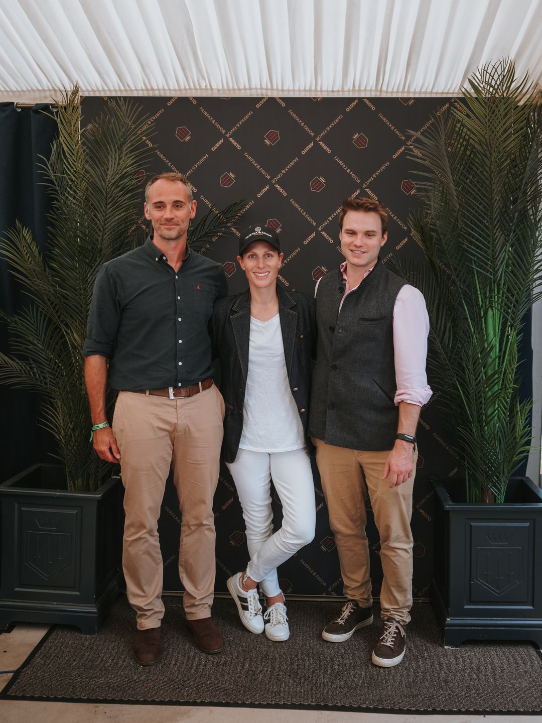 Zara Tindall in a white outfit standing with two men