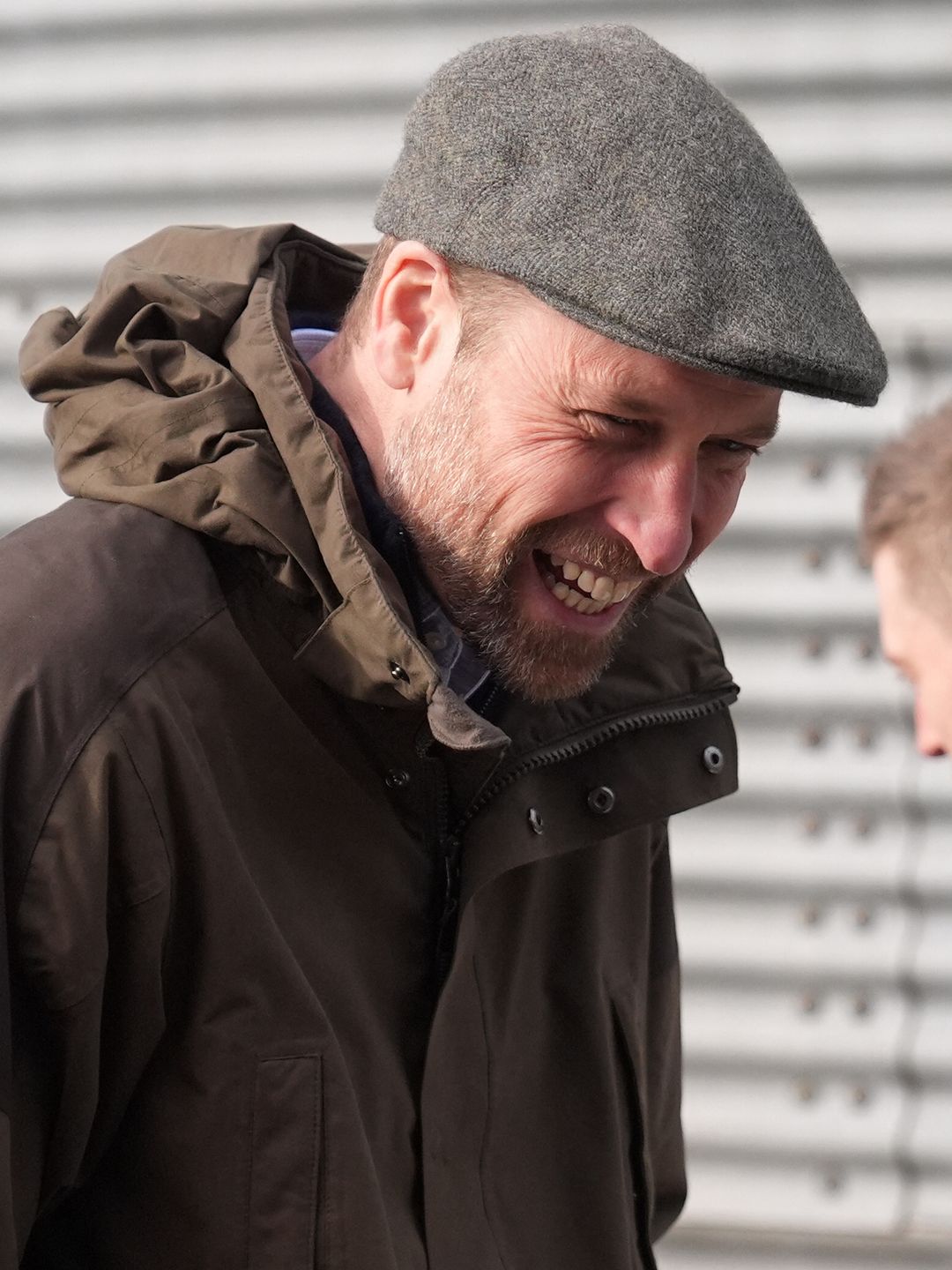 man smiling in waterproof coat and flat cap