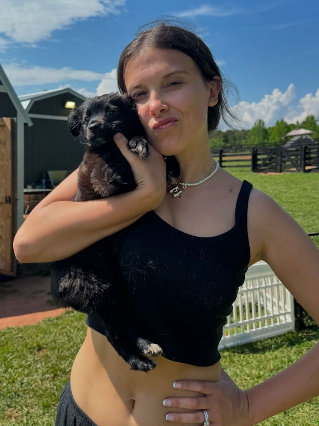 Millie Bobby Brown poses on her Instagram in a black crop tank top holding a puppy 