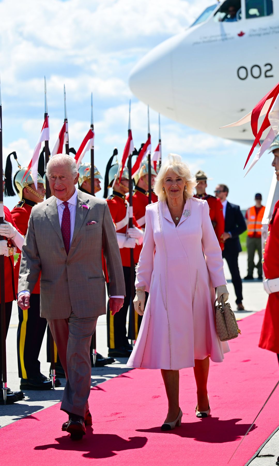 King Charles and Queen Camilla walking past guards