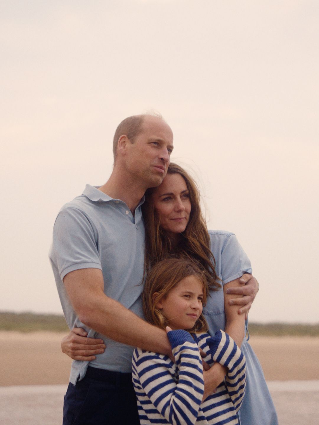 William and Kate embracing Charlotte on a beach