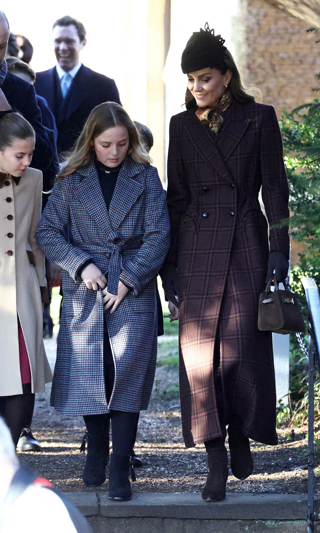 The Princess of Wales and family on Christmas Day 2025 walk out of Sandringham church. Kate wears a long brown coat and matching accessories