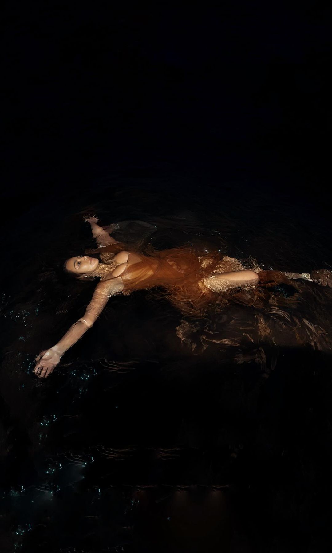 Kim Kardashian poses in the ocean wearing a brown tulle dress