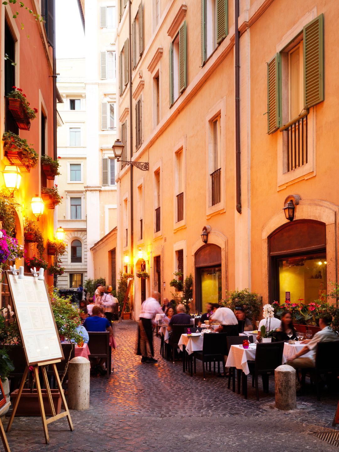 Italy, Lazio, Rome, Trastevere district, people dining outside restaurants at dusk