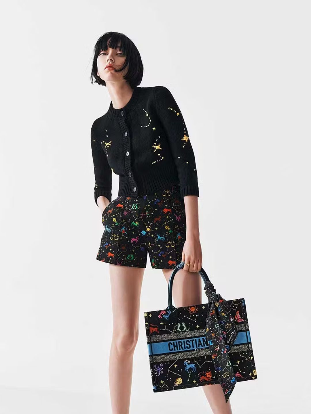 A Dior model poses for a campaign image wearing a black cardigan and shorts 