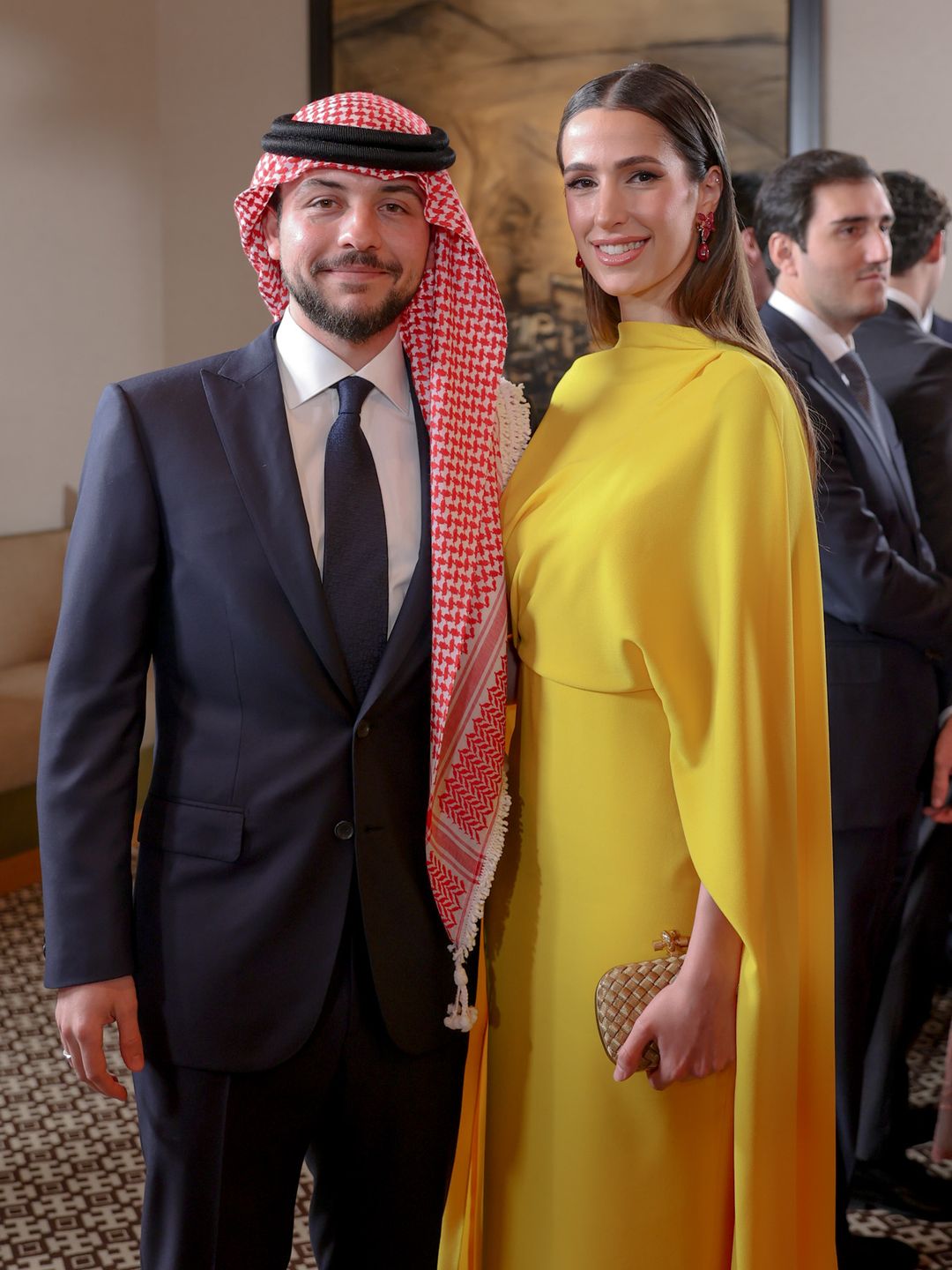 Crown Prince Hussein standing with Princess Rajwa, who wears a yellow dress