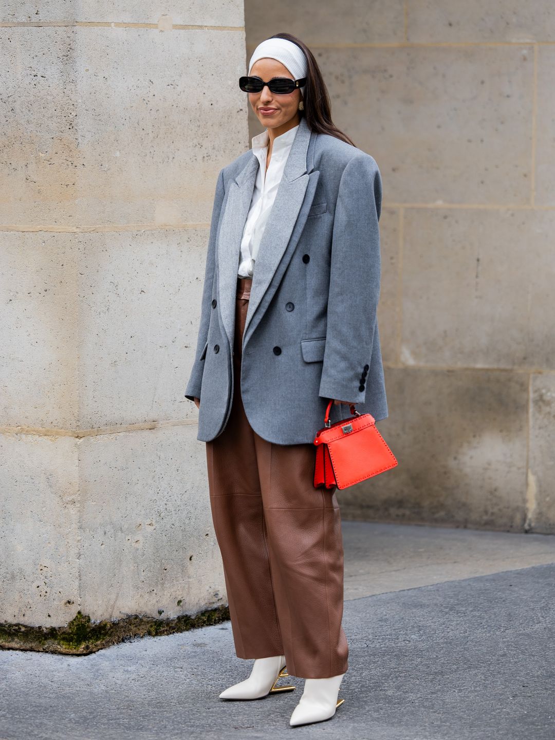 Bettina Looney wears white head band, brown pants, grey oversized blazer, red bag, white blouse outside Fendi during the Haute Couture 