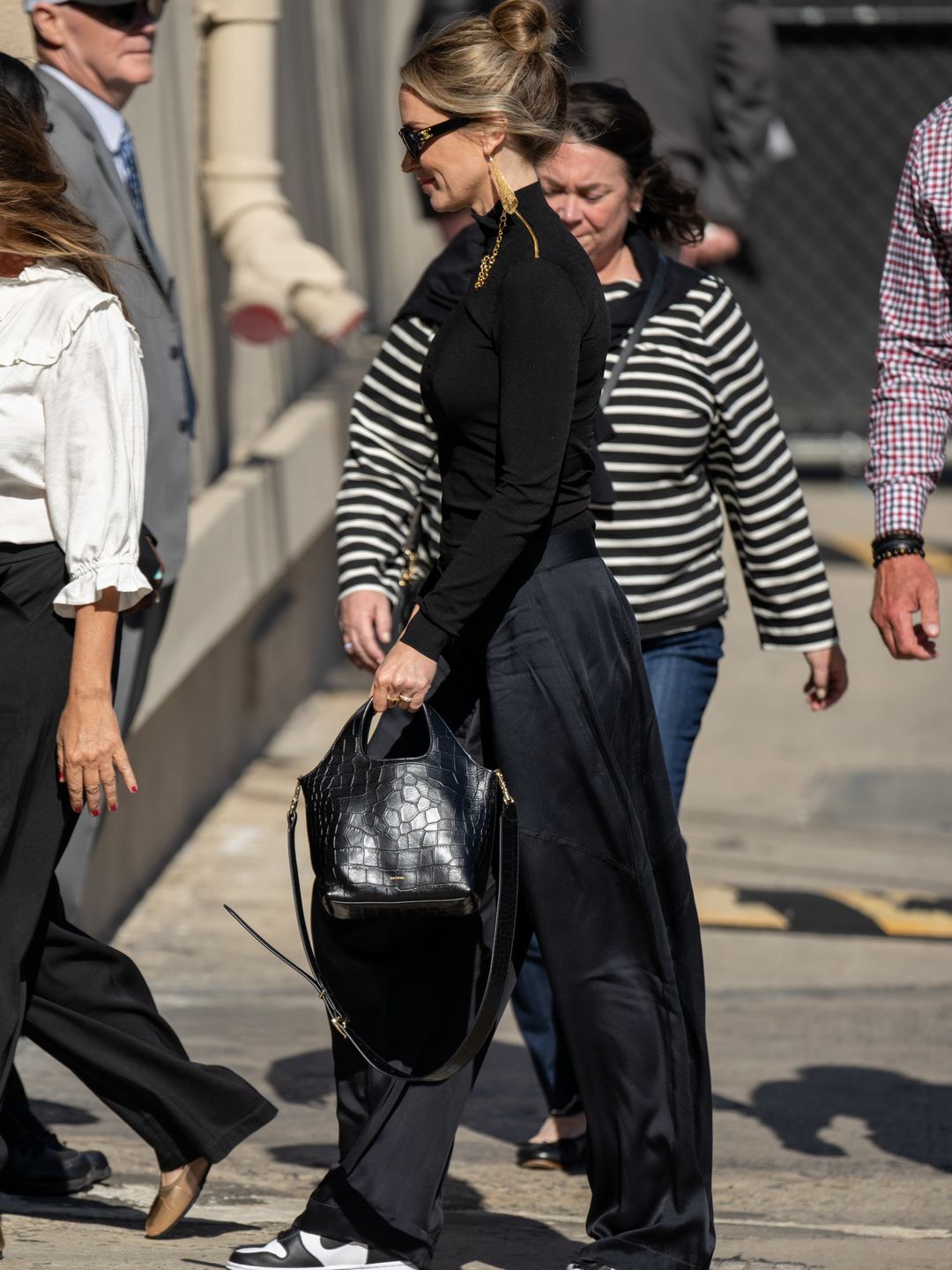 Emily Blunt wearing black turtleneck, croc-effect bag and Nike Dunks 