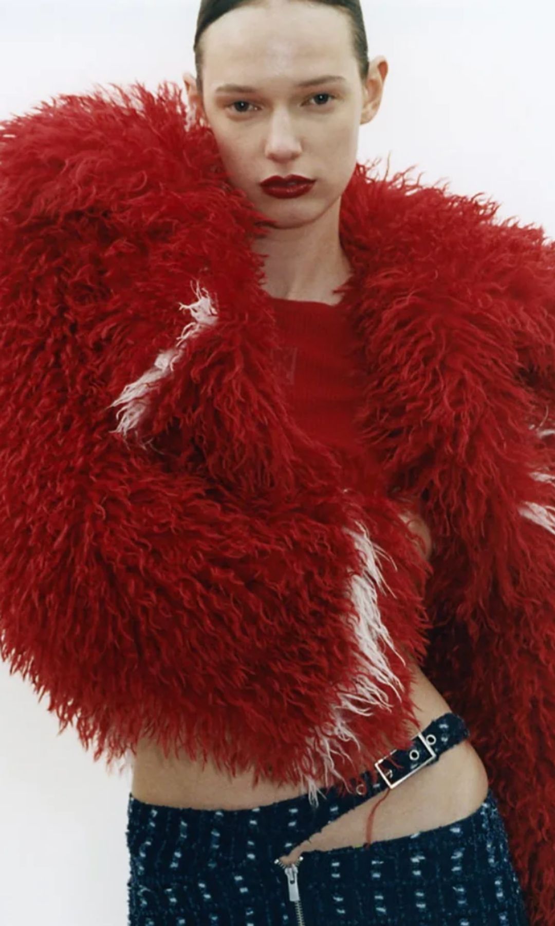 A model poses in a red fluffy jacket from JAKKE