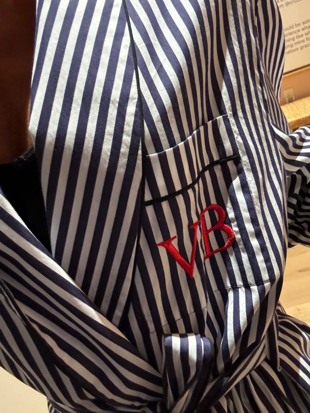 Victoria Beckham wears a striped dressing gown with her initials embroidered in red thread