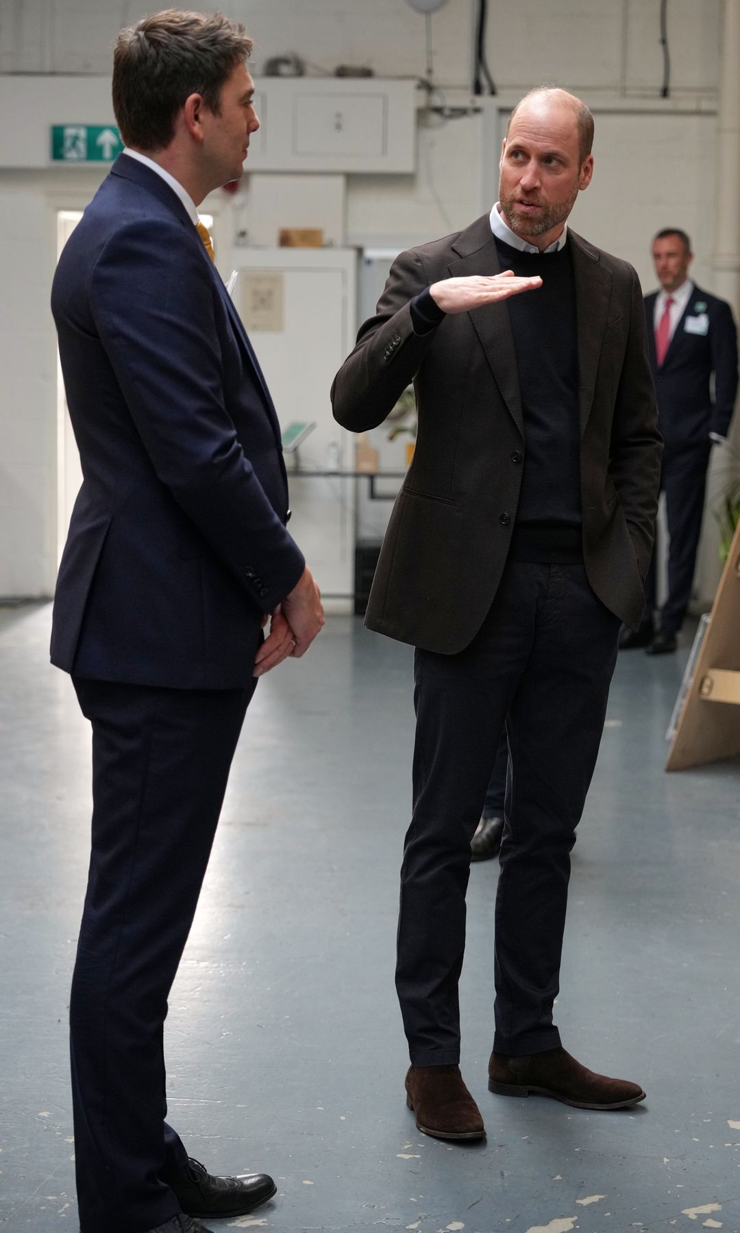 Prince William speaking with a man, holding his hand up