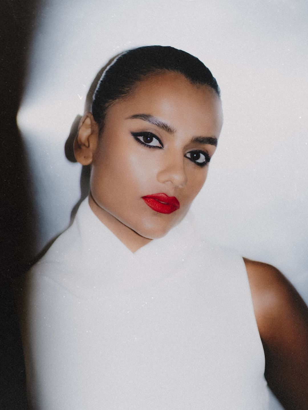 Simone Ashley poses in a red lip look and smokey eye