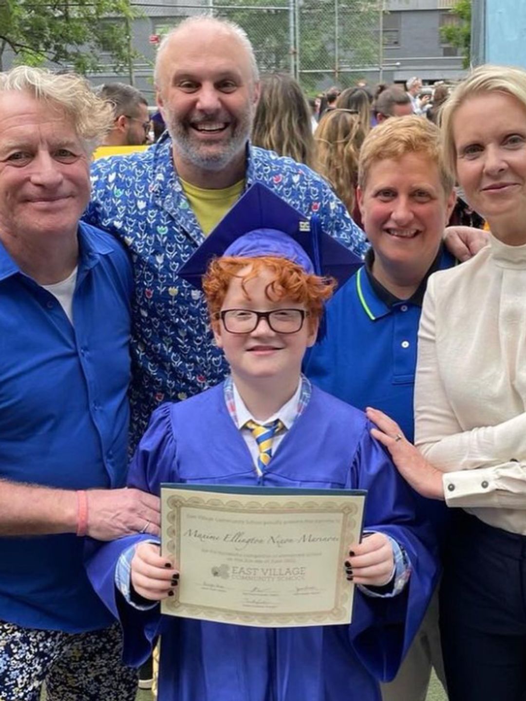 Cynthia Nixon, her wife and their family with a ginger boy in a blue gown holding a graduation certificate