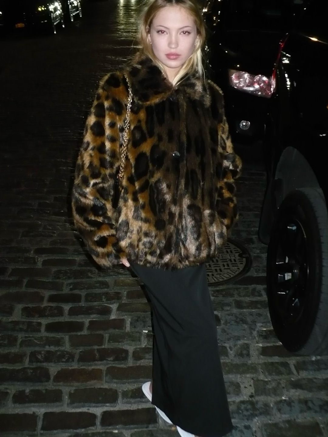 Lila Moss poses in a leopard print jacket, a black maxi dress and a set of hotel slippers on her Instagram 