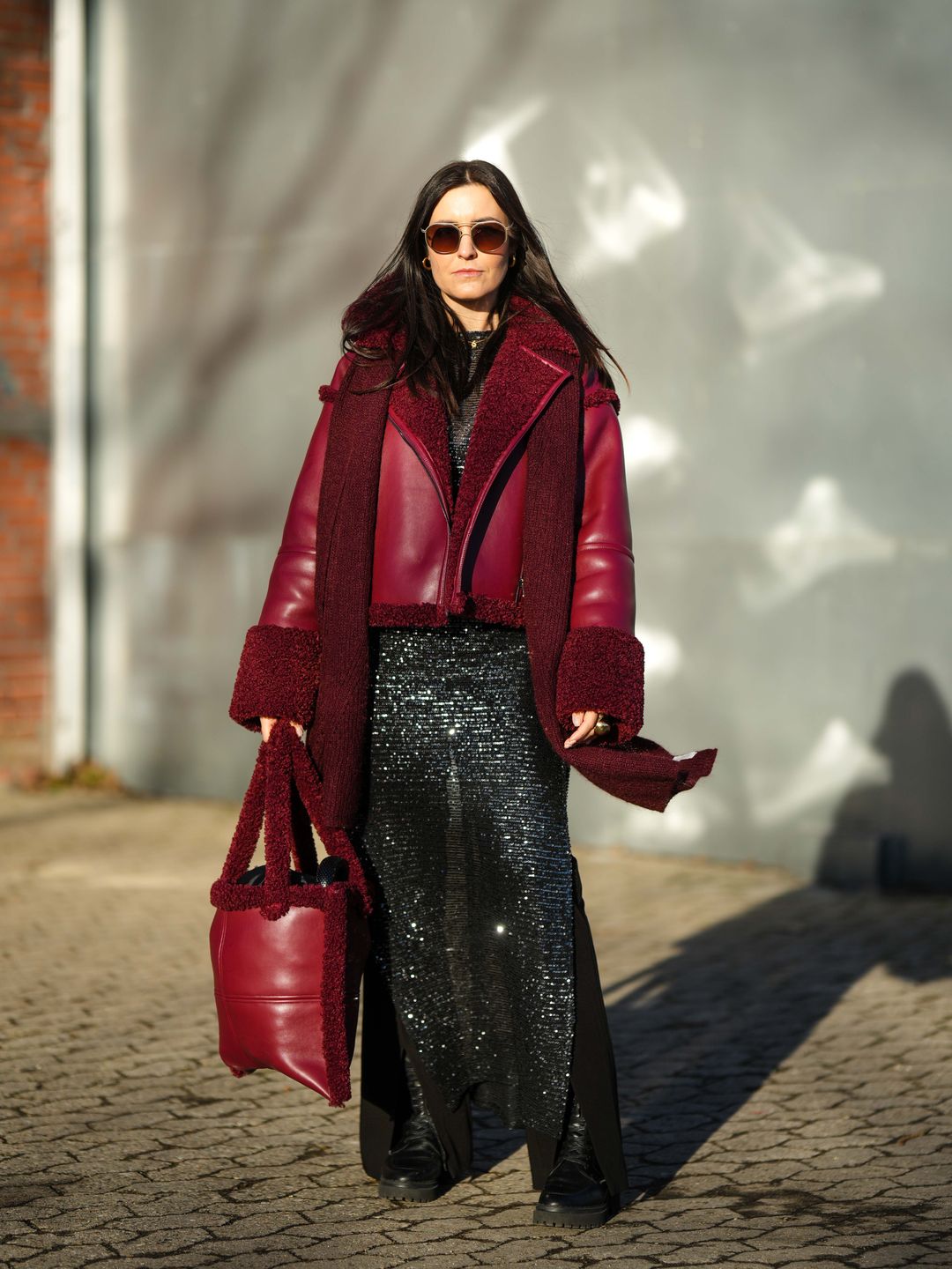 Woman wearing sheer glittery dress with red shearling jacket 