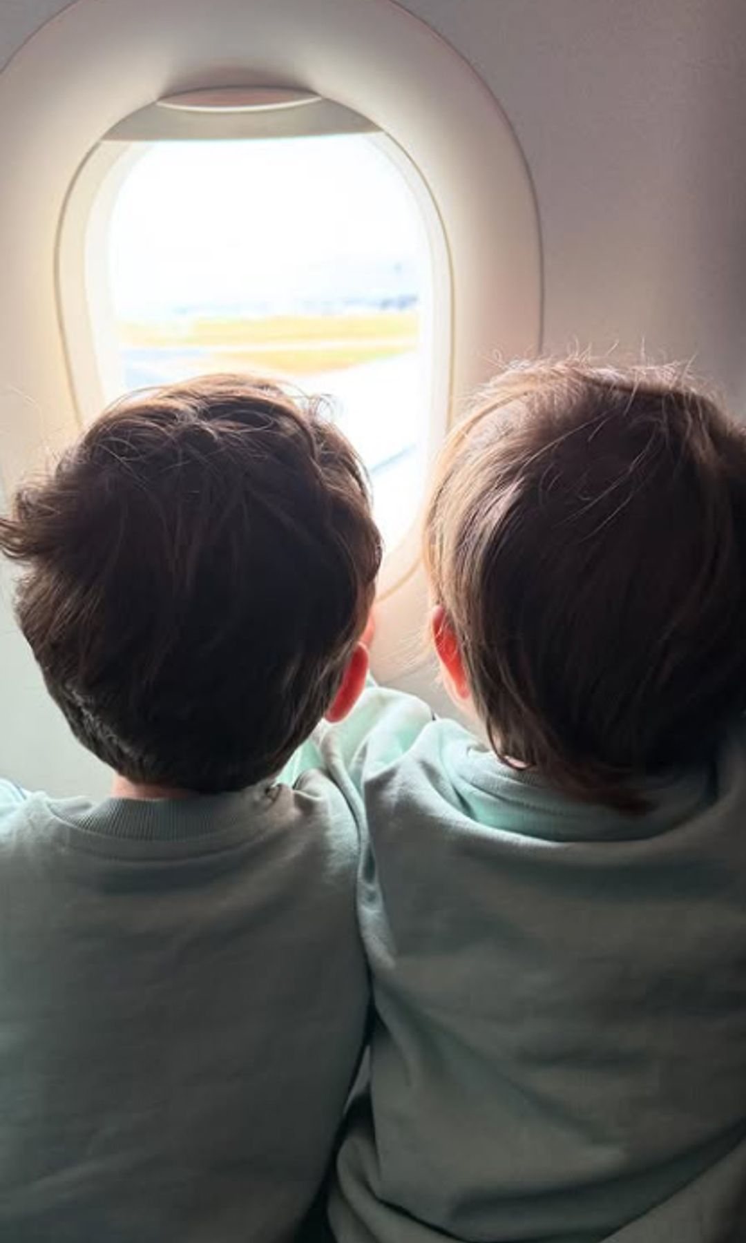Two young children looking out of the window on an aeroplane