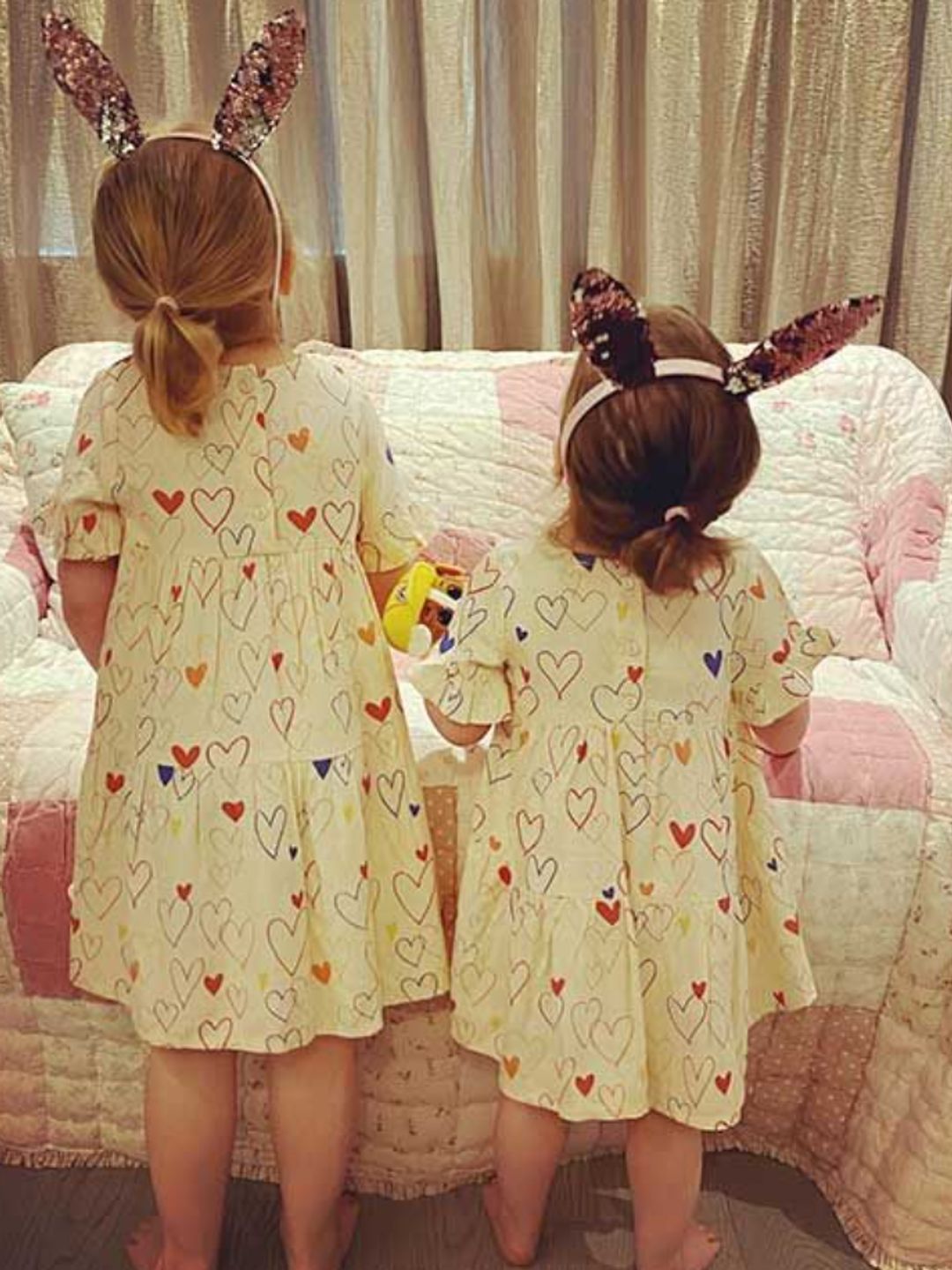 Two young girls in white dresses with hearts and bunny ears