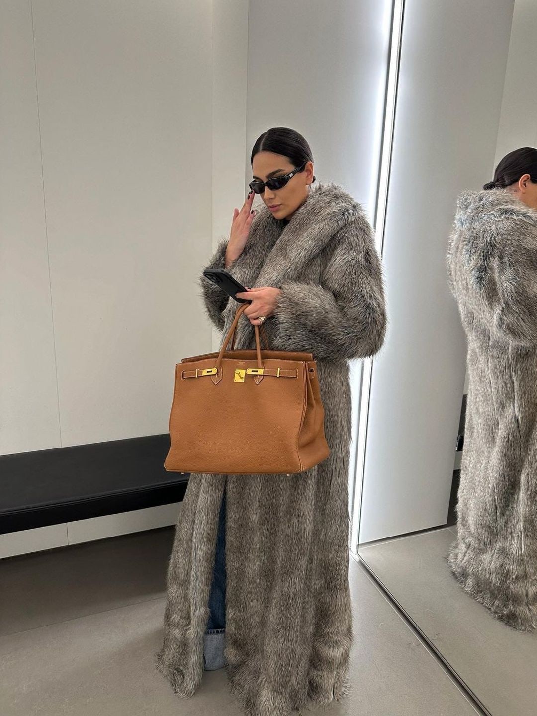 Style influencer @charlotteemilysanders wears a long fur coat, black sunglasses and a birking bag 