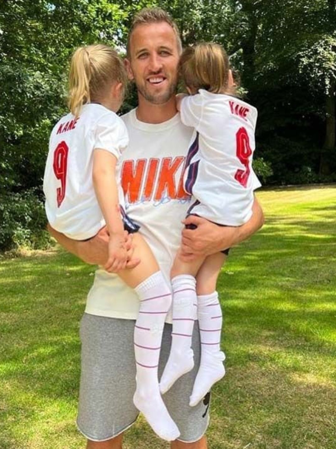 Harry Kane carrying two young girls in football kits