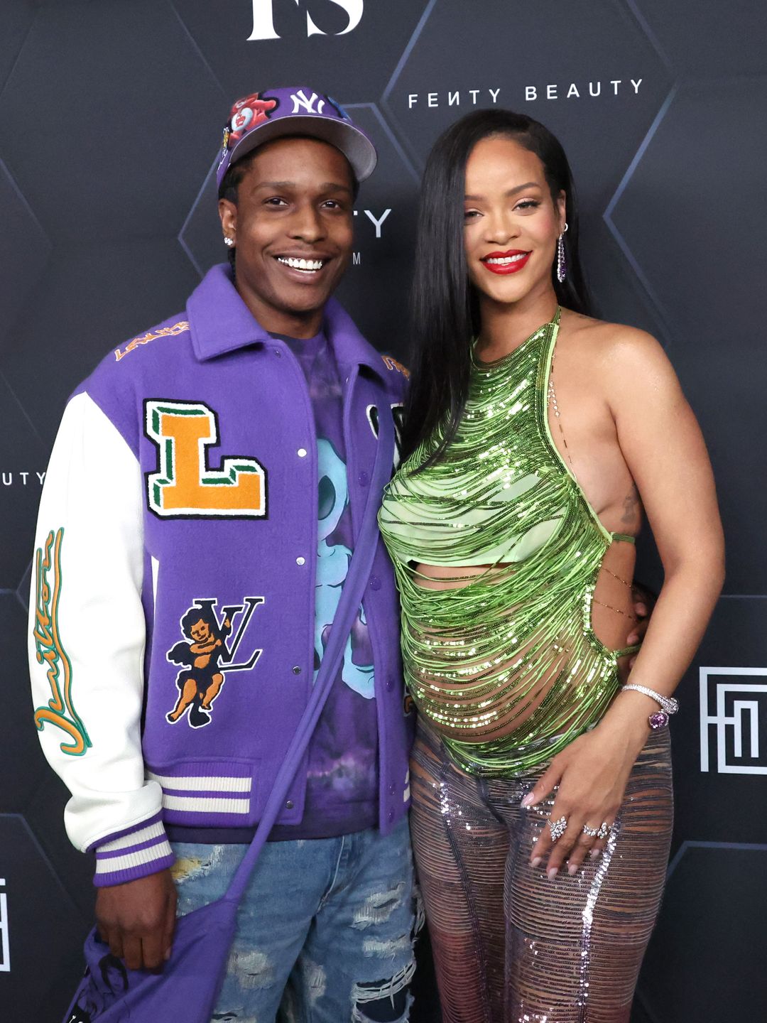 Rihanna and ASAP Rocky smiling on a red carpet, she is visibly pregnant