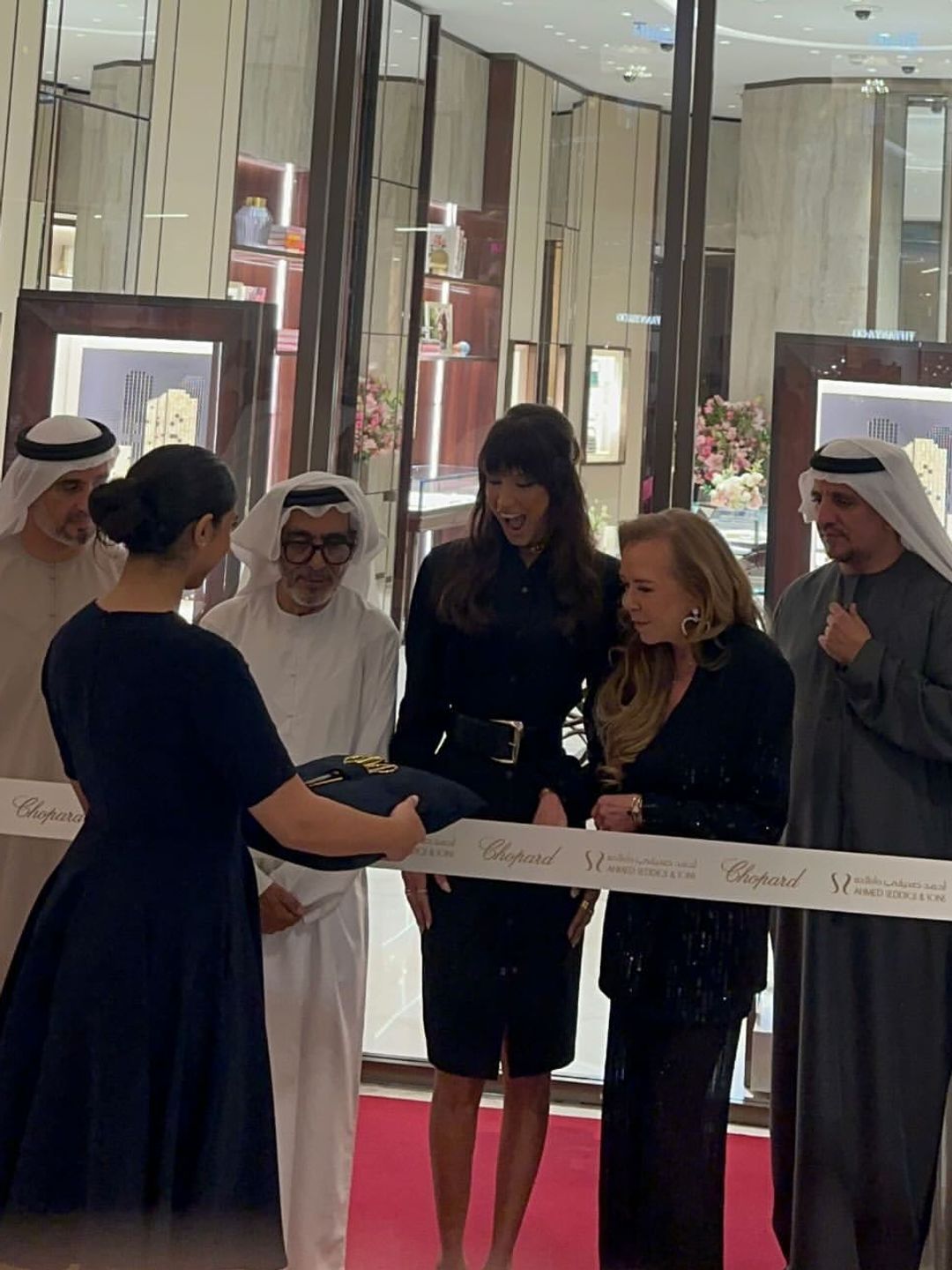 Bella Hadid is seen in a black dress cutting the ribbon into the Dubai store alongside Co President and Artistic Director of Chopard, Caroline Scheufele