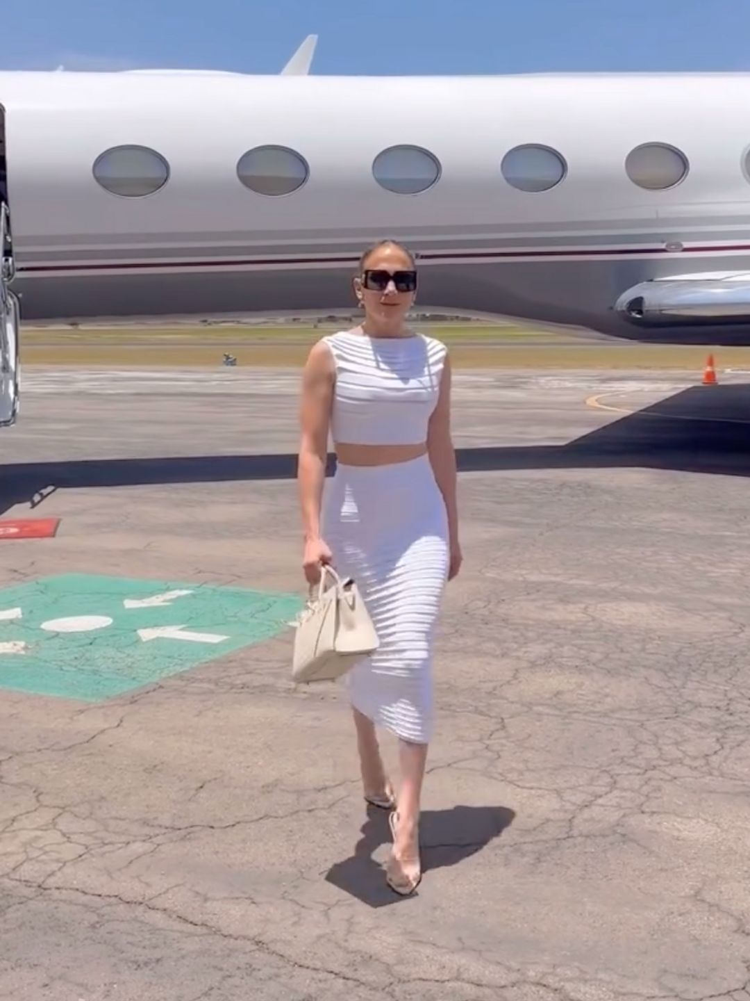 Jennifer Lopez poses at the airport in a body con white twin set