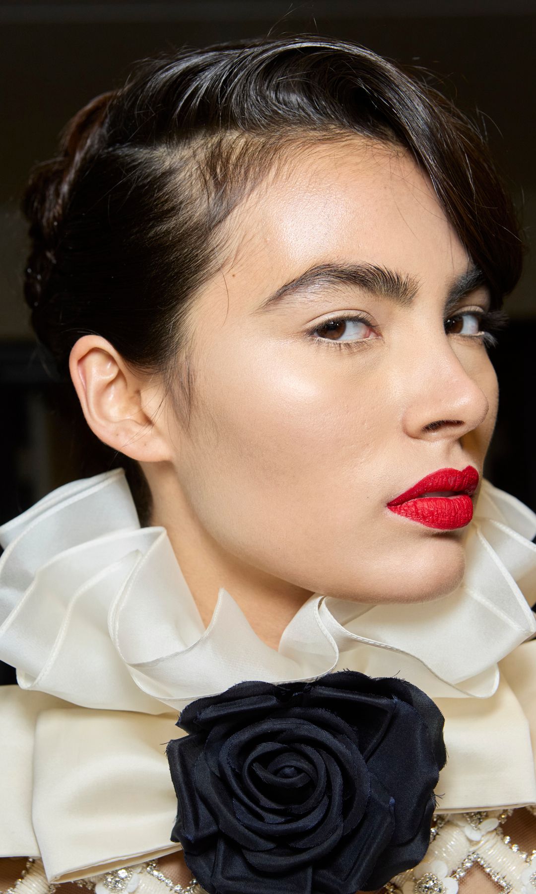 A model with very dark brown hair and red lipstick at the Richard Quinn AW24 show