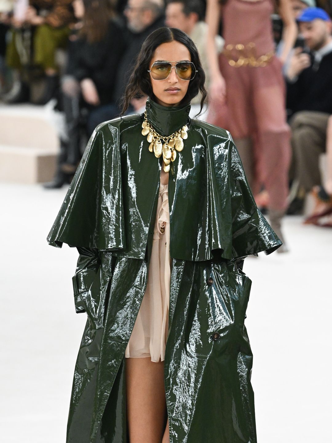 A model walks the runway during the Chloé Womenswear show in a patent green trench coat