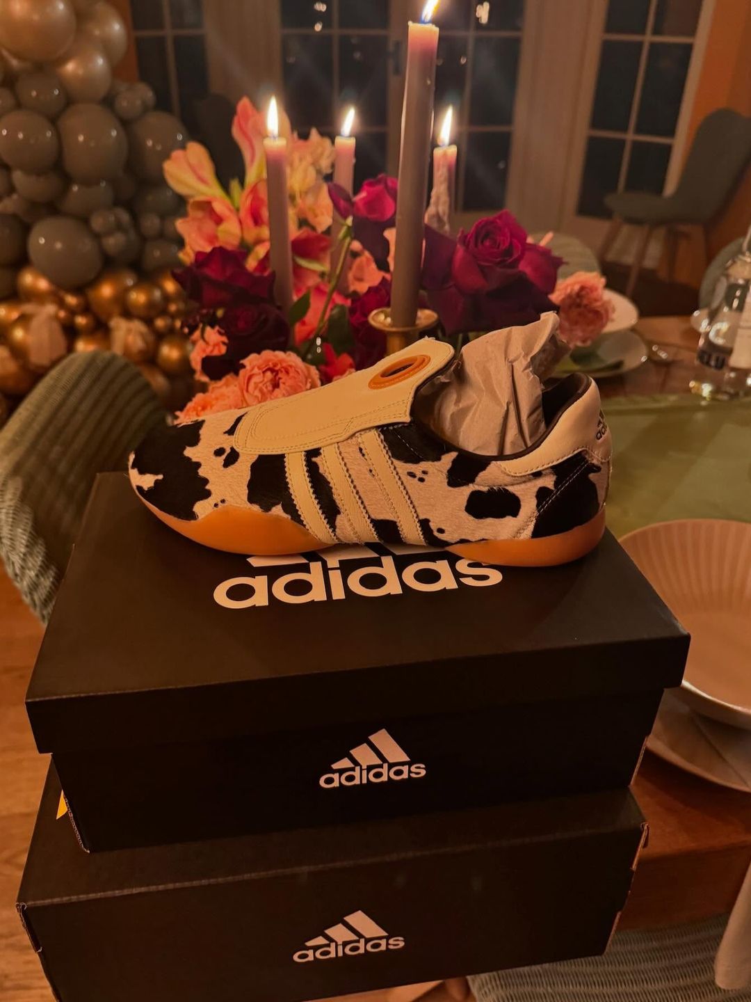 A pair of adidas cow print sneakers on a box