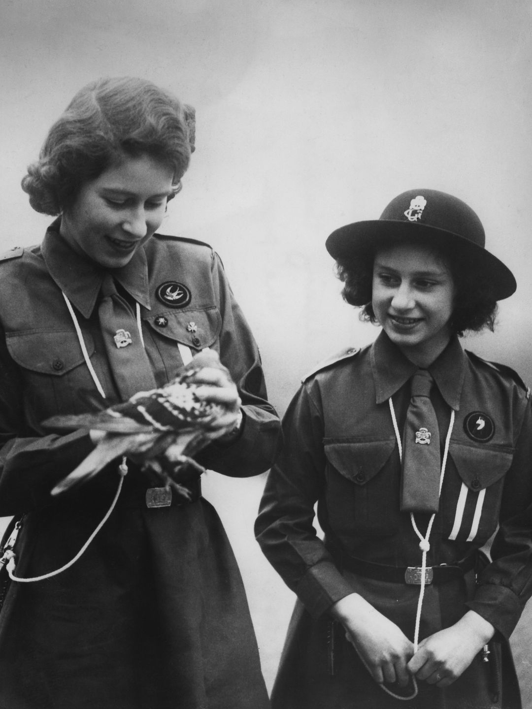 Black-and-white photo of the Queen and Princess Margaret with a pigeon
