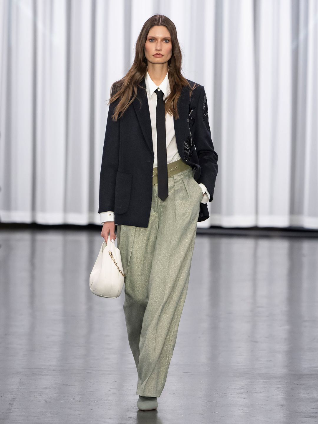Marc Cain model wears sage green pants, a white shirt tie and blazer look