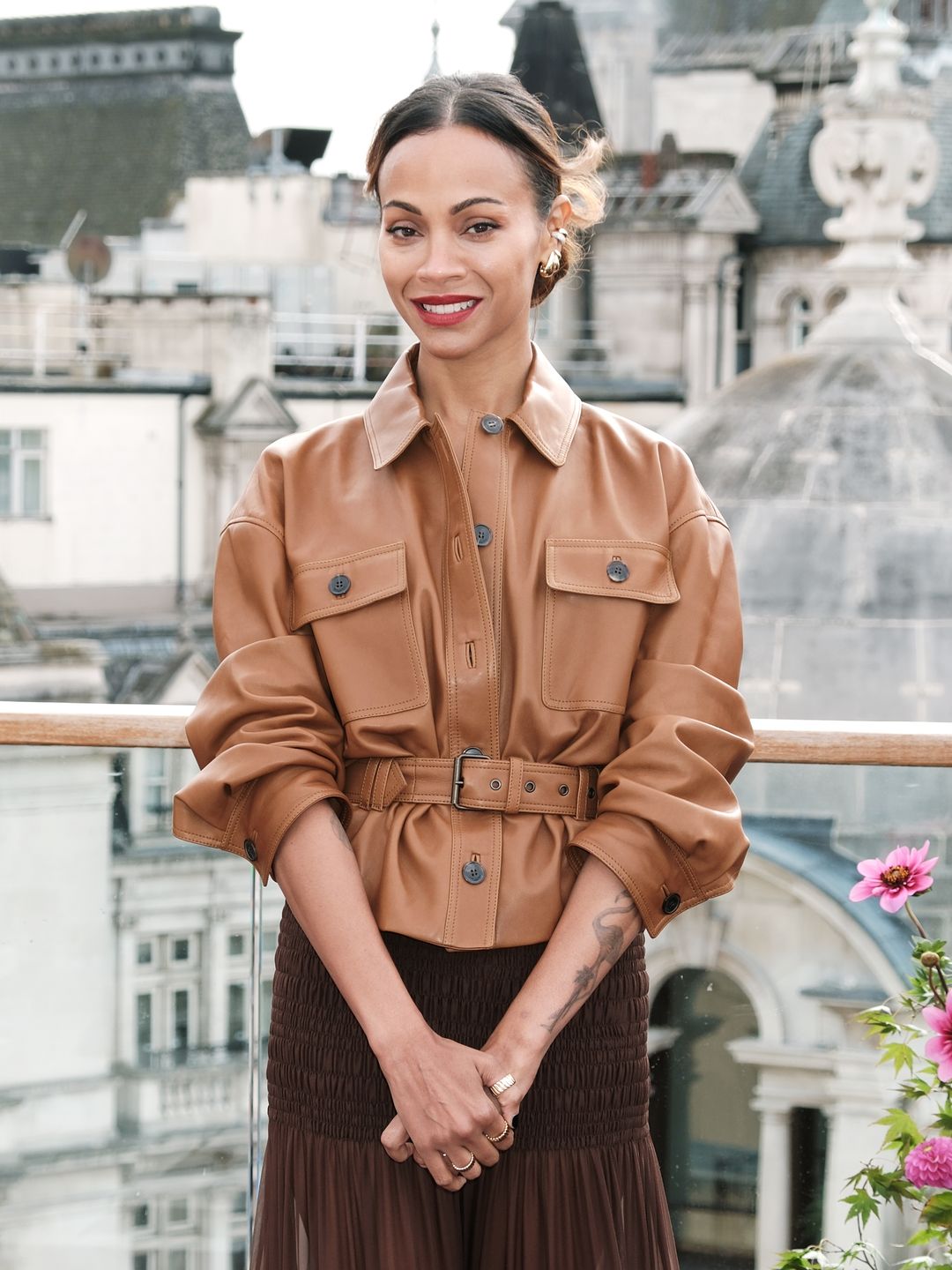 Zoe Saldana in a brown leather jacket and skirt