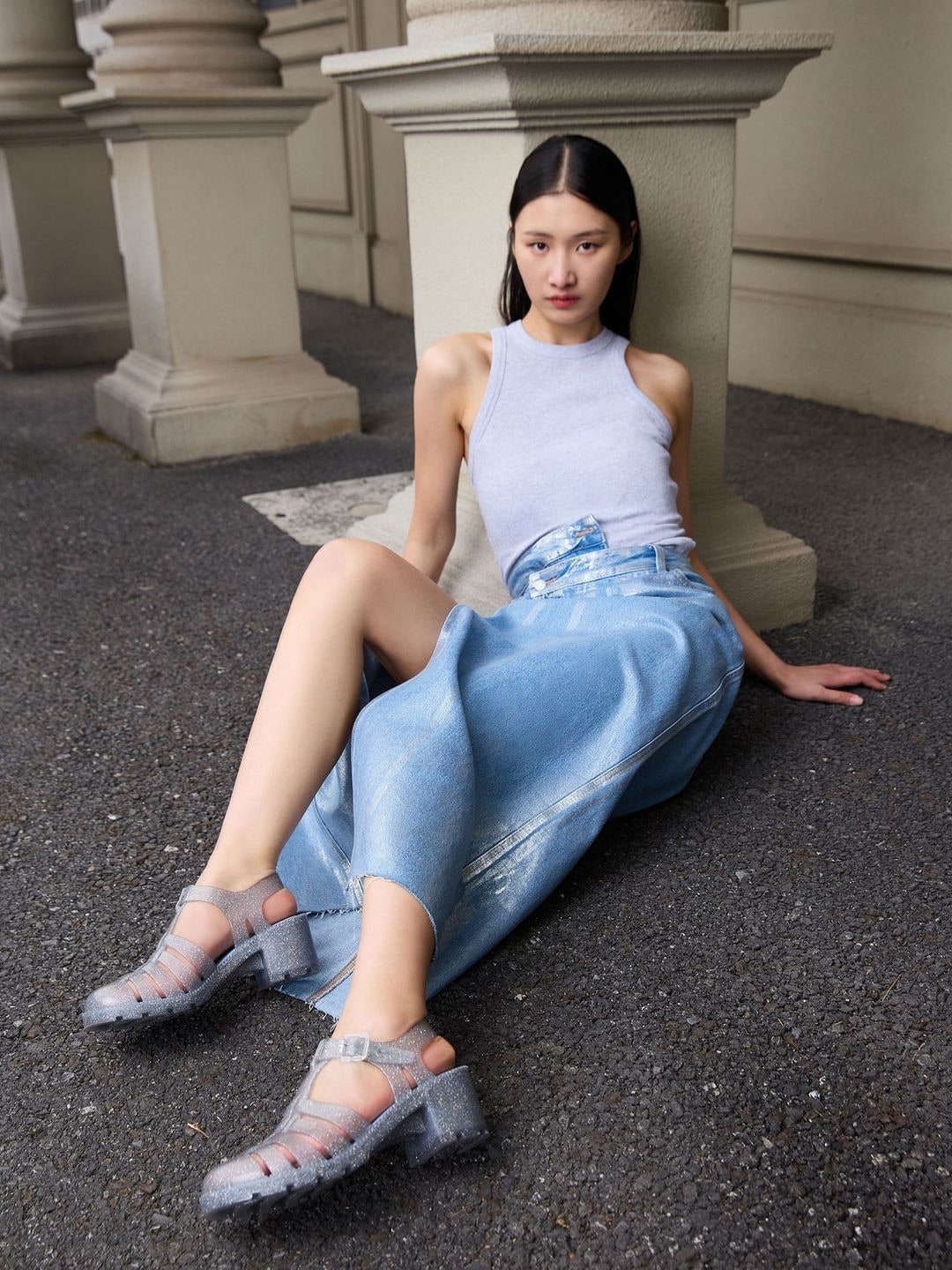 A model poses in a jean skirt and tank top for footwear brand Melissa.