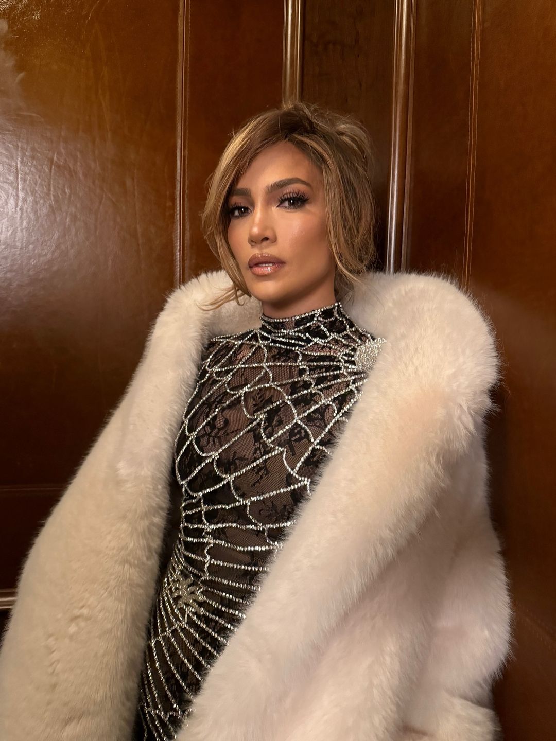 Jennifer Lopez poses in a spider web sheer dress and fluffy white coat at Sundance Film Festival 2025