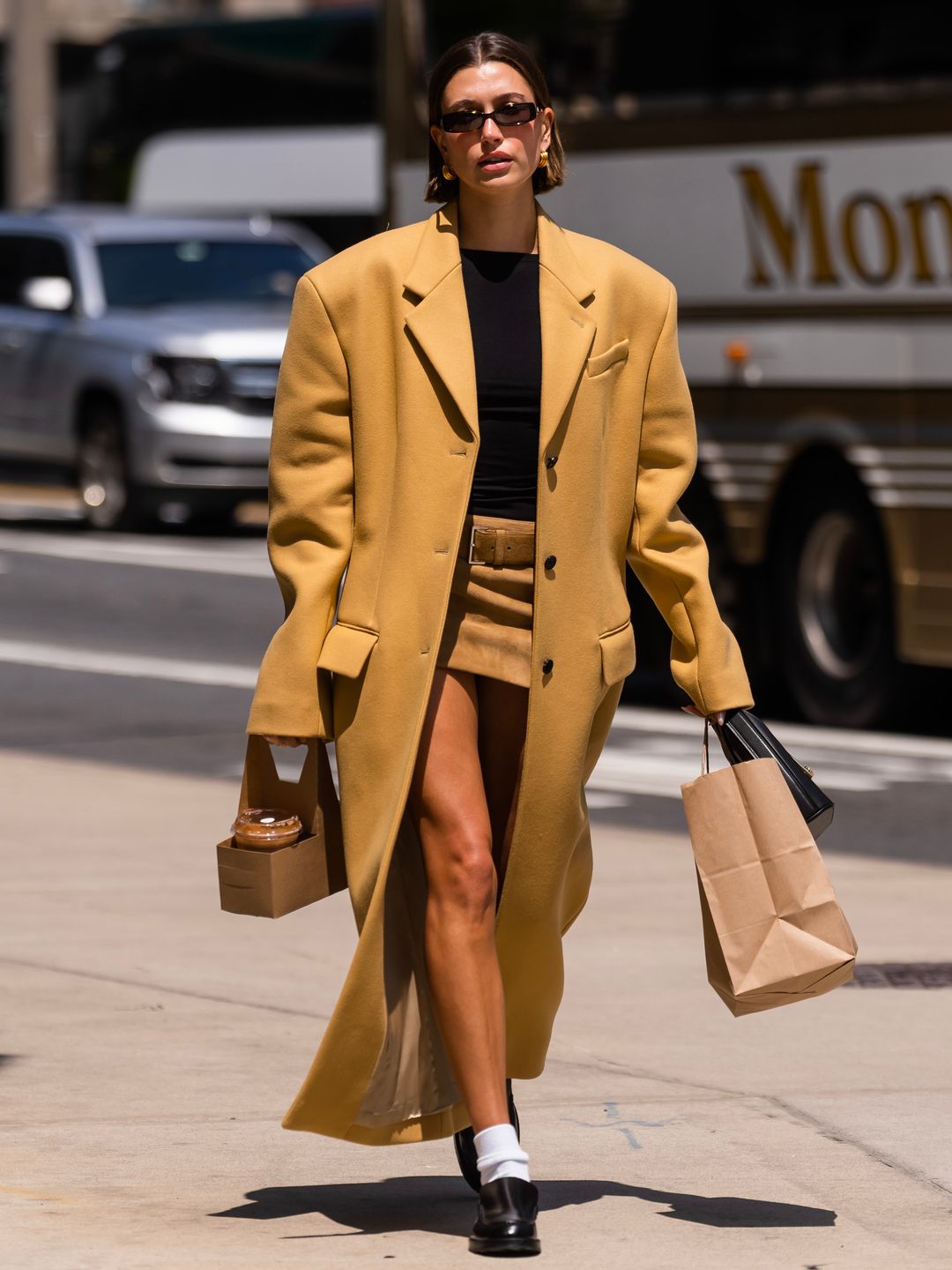 Hailey Bieber is seen in Tribeca on May 10, 2023 wearing a mustard coat with white socks and loafers