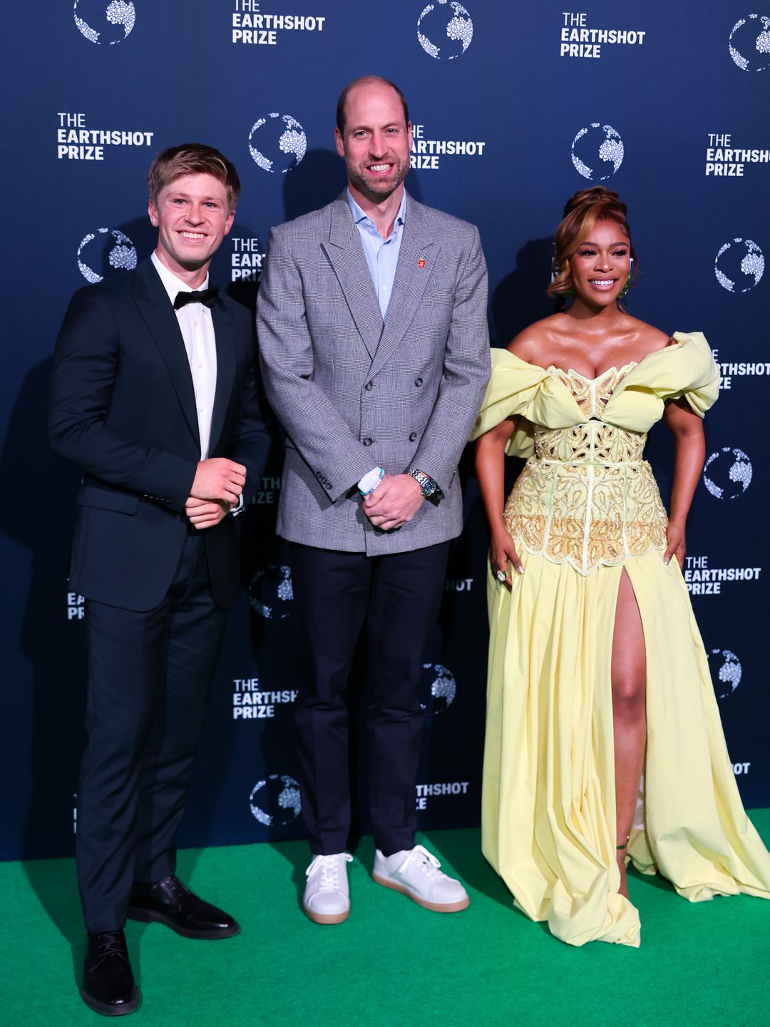 three people posing on green carpet