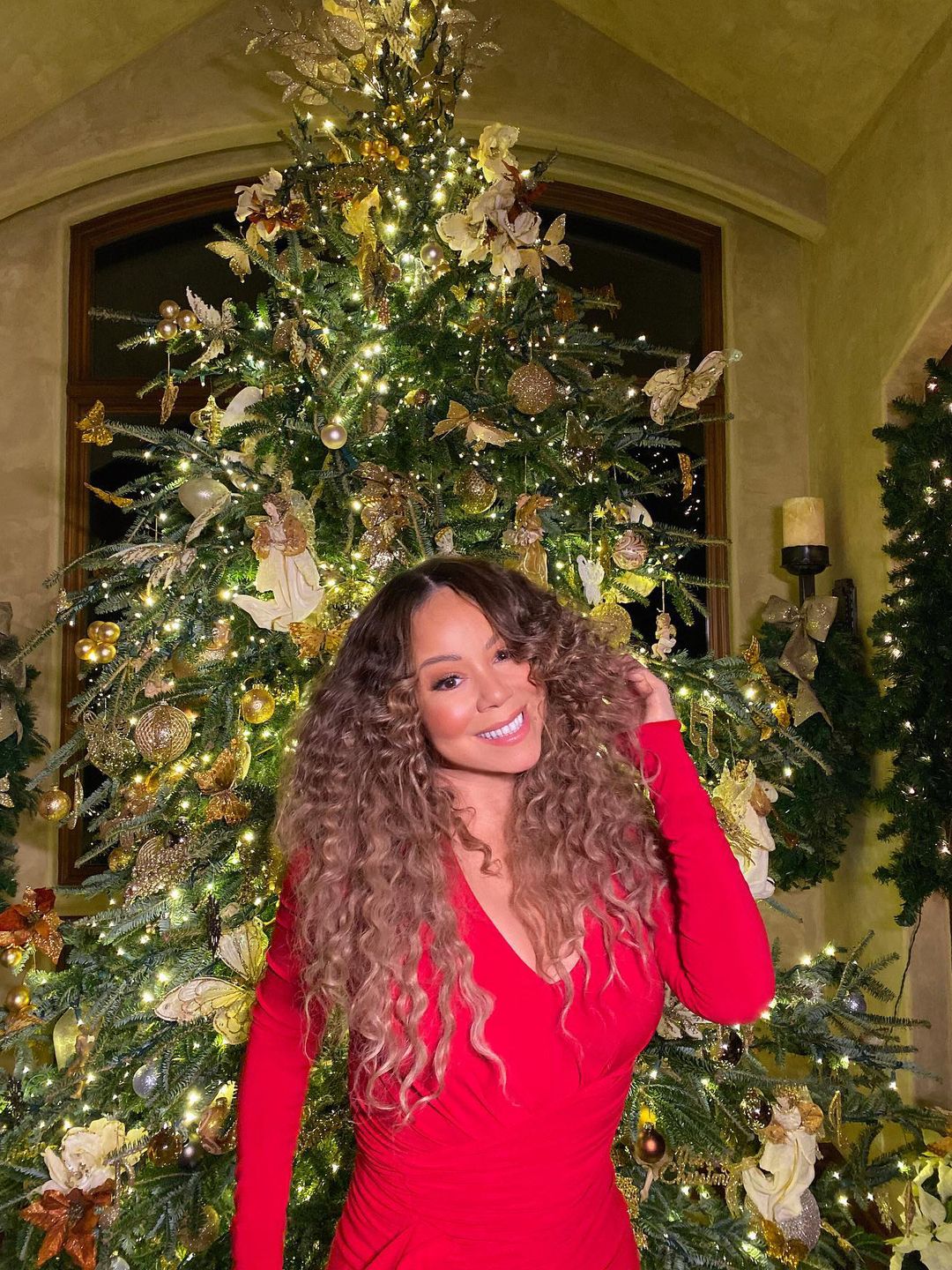 Mariah Carey standing by her Christmas tree. 