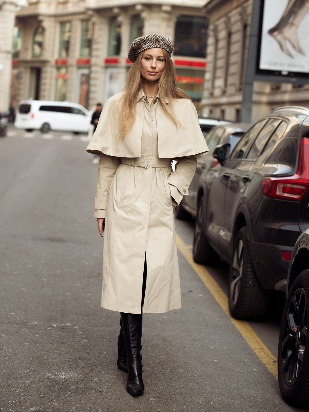 A guest wears a beret, grey trench coat, and black long boots outside Del Core during the Milan Fashion Week