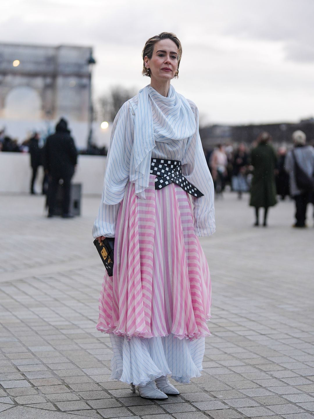 Sarah Paulson wears a white striped shirt with oversized sleeves, a pink and white striped skirt, outside Louis Vuitton, during the Womenswear Fall/Winter 2024/2025