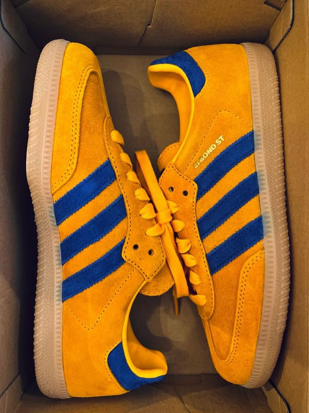 A photo of yellow and blue Adidas Samba's in their box
